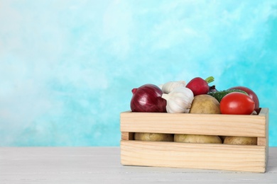 Photo of Wooden crate with vegetables on table, space for text