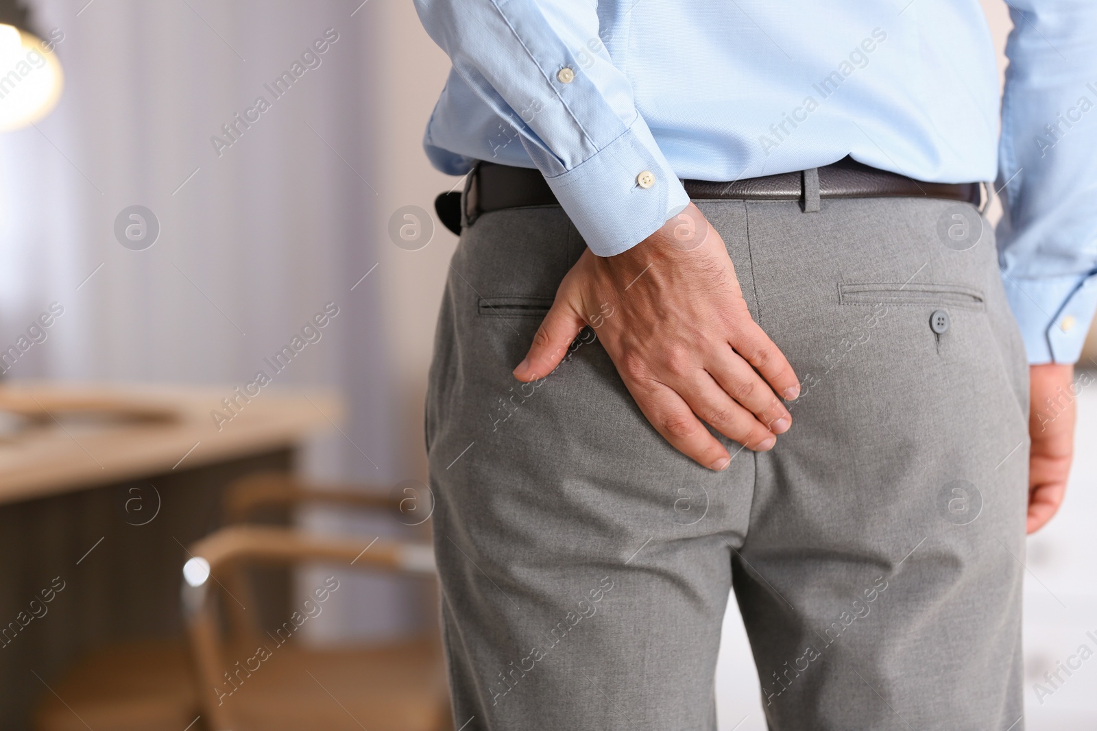 Photo of Man suffering from hemorrhoid in office, closeup