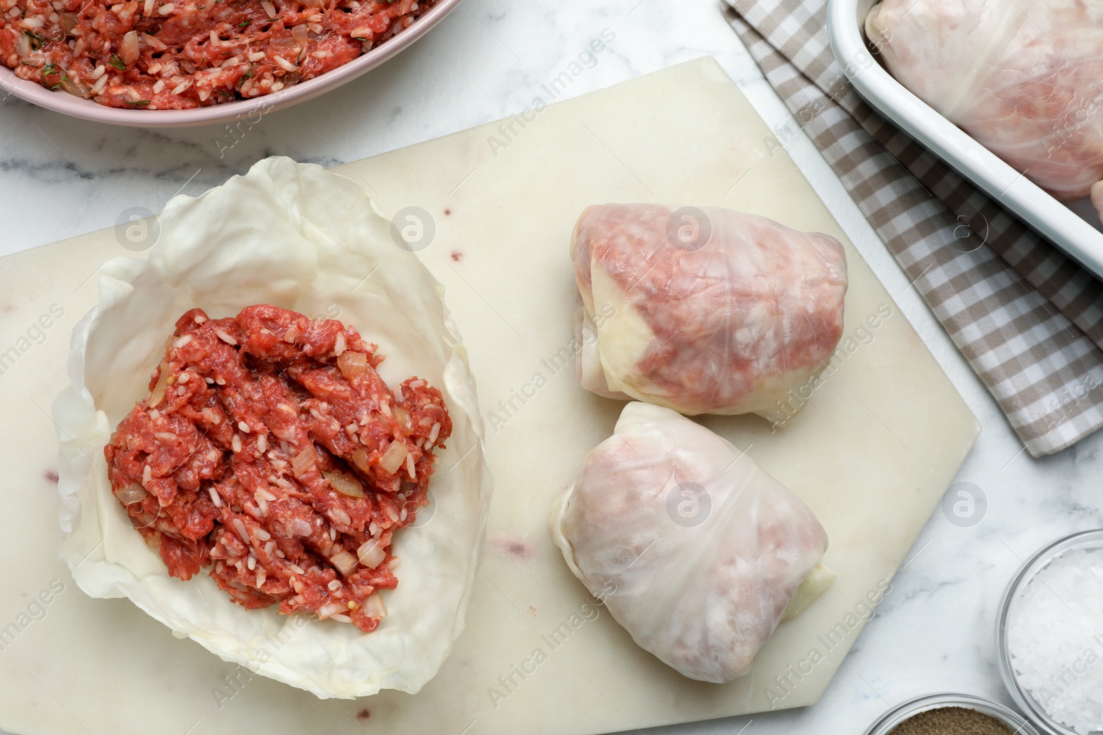 Photo of Preparing stuffed cabbage rolls on white marble table, flat lay