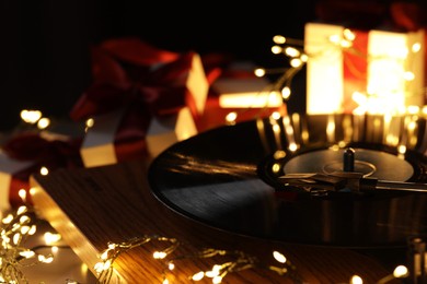 Photo of Turntable with vinyl record, fairy lights and Christmas gift boxes, closeup