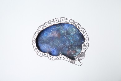 Photo of Imaginative thinking. Drawing of galaxy, top view through paper with brain shaped hole