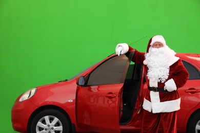 Photo of Authentic Santa Claus near car against green background
