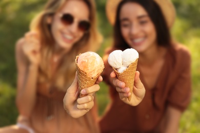 Photo of Young women with ice cream spending time together outdoors, focus on hands