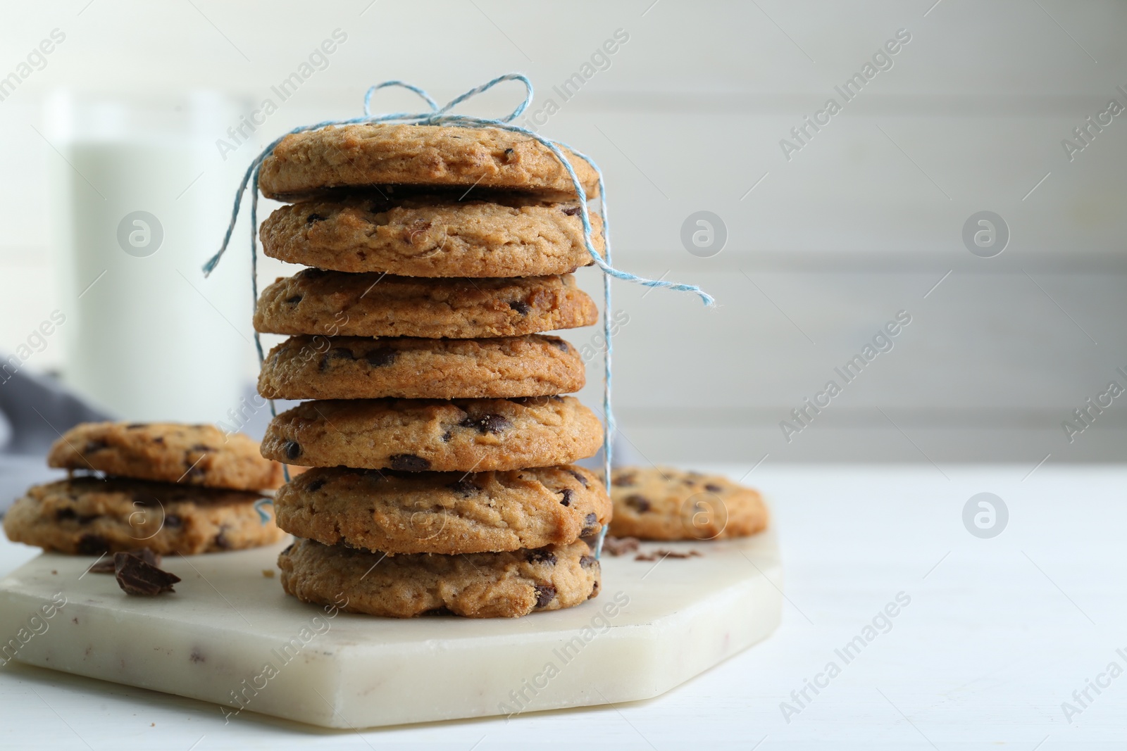 Photo of Tasty chocolate chip cookies on white wooden table, closeup. Space for text