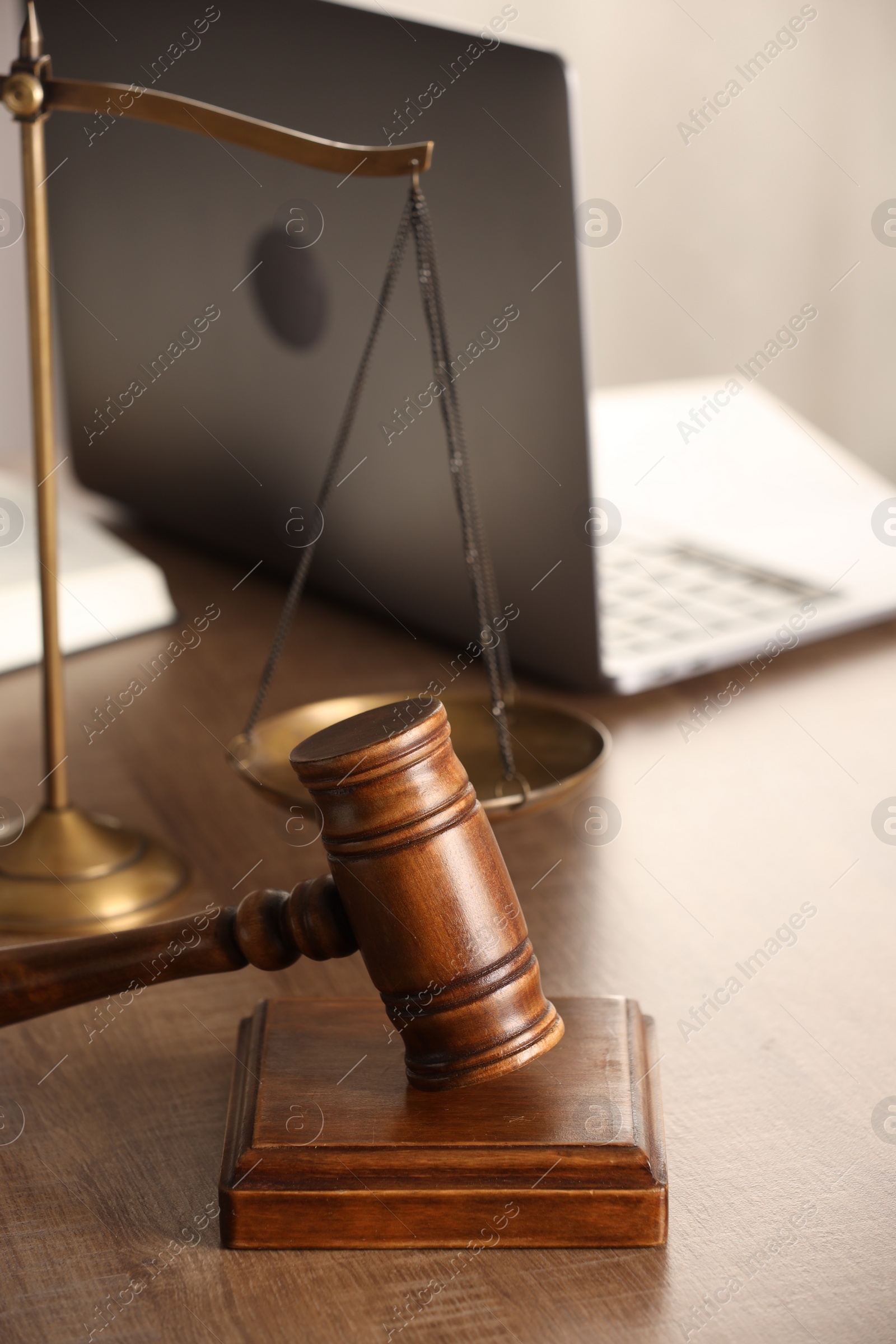 Photo of Law concept. Gavel, scales of justice and laptop on wooden table, closeup