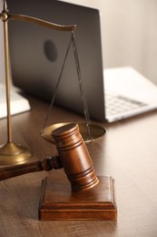 Photo of Law concept. Gavel, scales of justice and laptop on wooden table, closeup