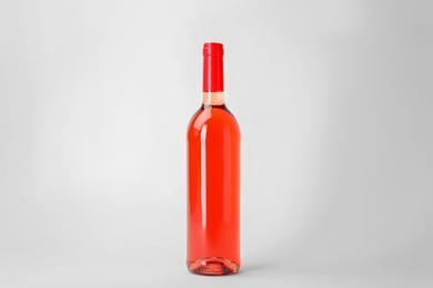 Photo of Bottle of expensive rose wine on light background