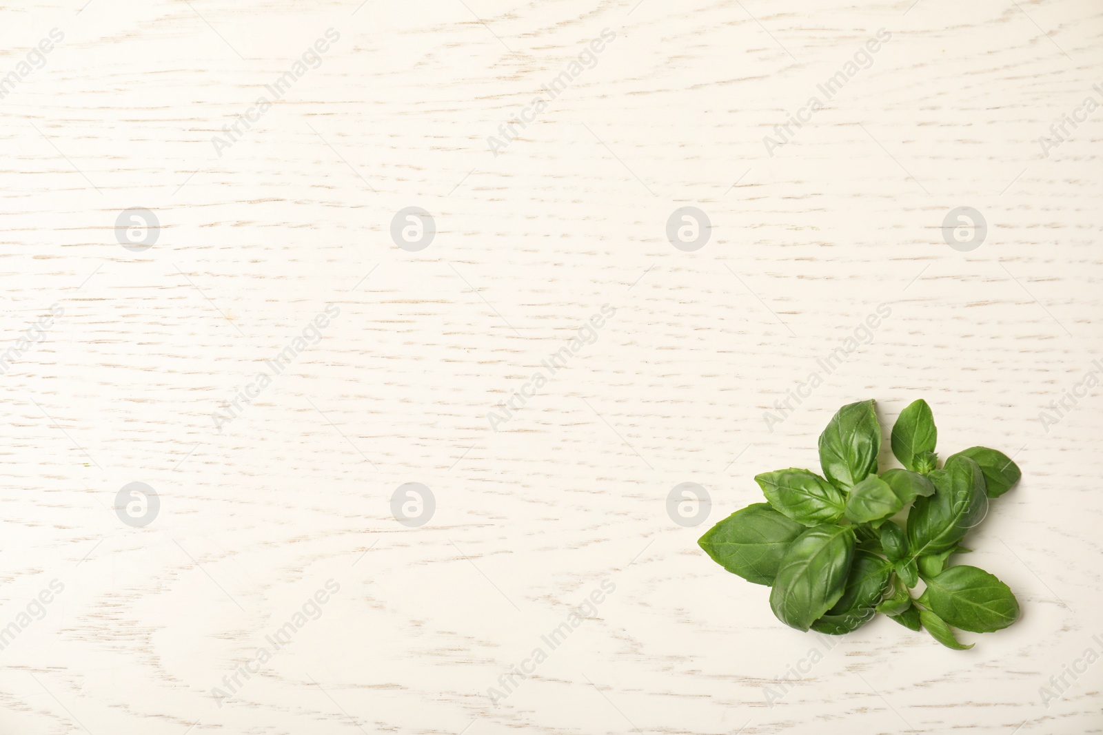 Photo of Fresh basil leaves on wooden background, top view. Space for text