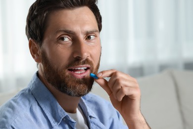 Photo of Handsome man taking pill indoors, space for text