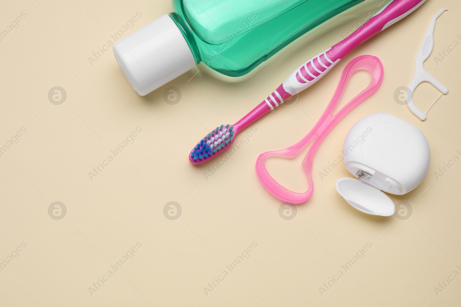 Photo of Tongue cleaner and other oral care products on beige background, flat lay. Space for text