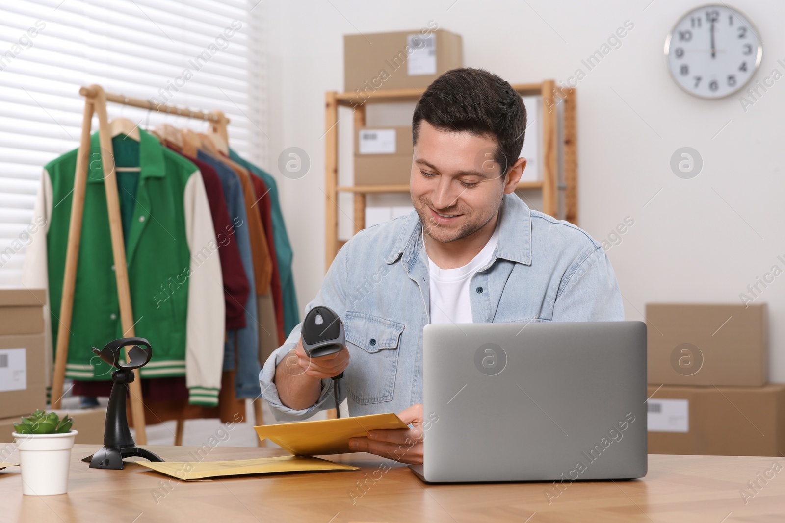 Photo of Seller with scanner reading parcel barcode in office. Online store