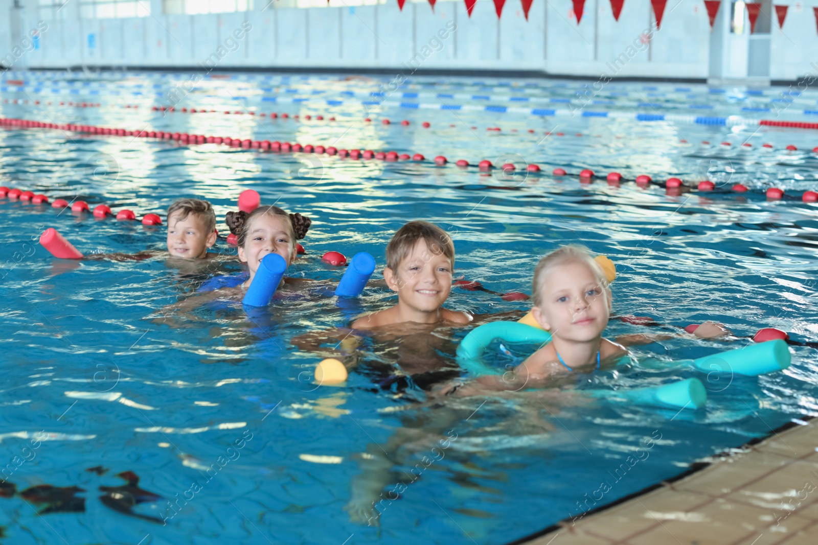 Photo of Little kids with swimming noodles in indoor pool