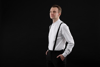 Handsome young man in white shirt on black background, space for text
