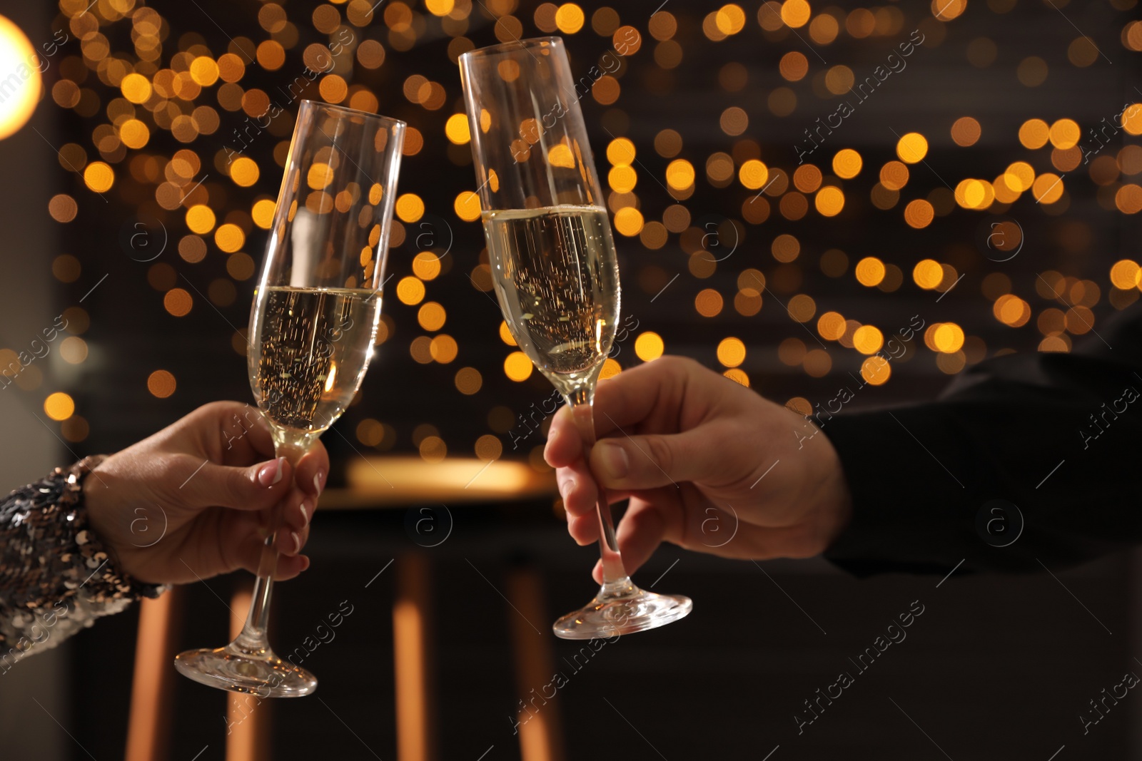 Photo of People clinking glasses of champagne indoors, closeup