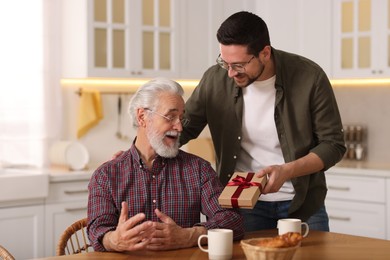 Photo of Son giving gift box to his dad at home