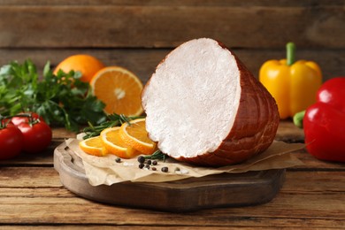 Photo of Delicious ham with rosemary, peppercorns and orange slices on wooden table