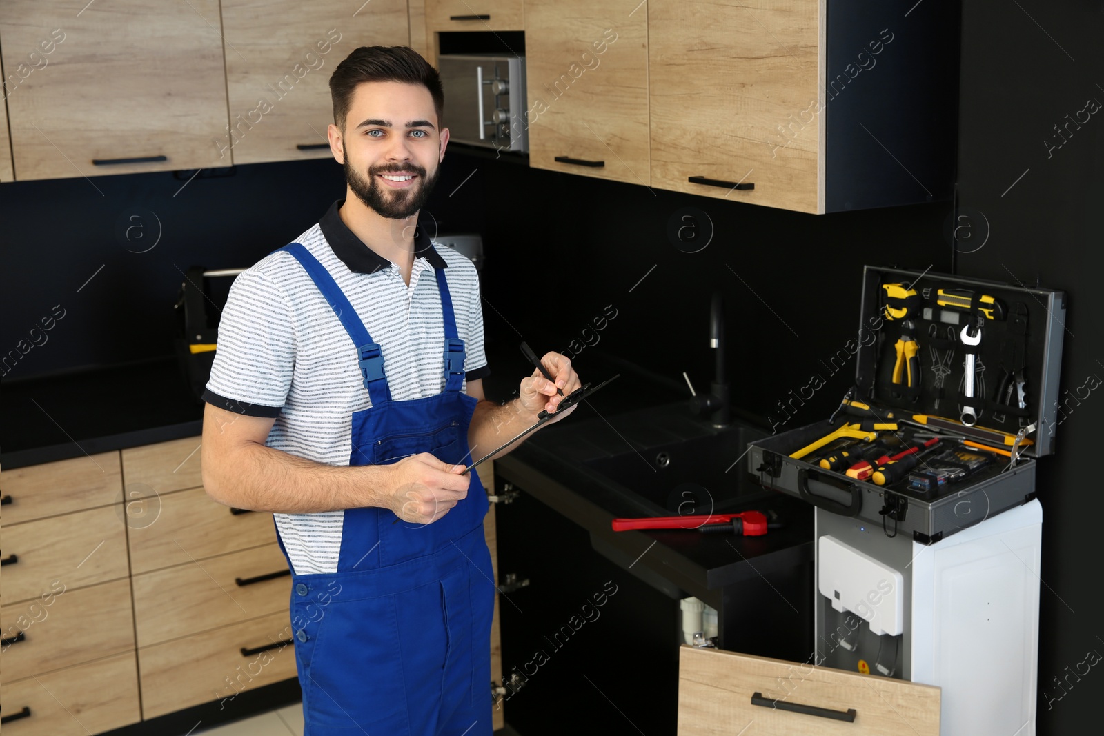 Photo of Male plumber with clipboard in kitchen. Repair service