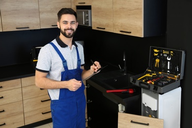 Photo of Male plumber with clipboard in kitchen. Repair service