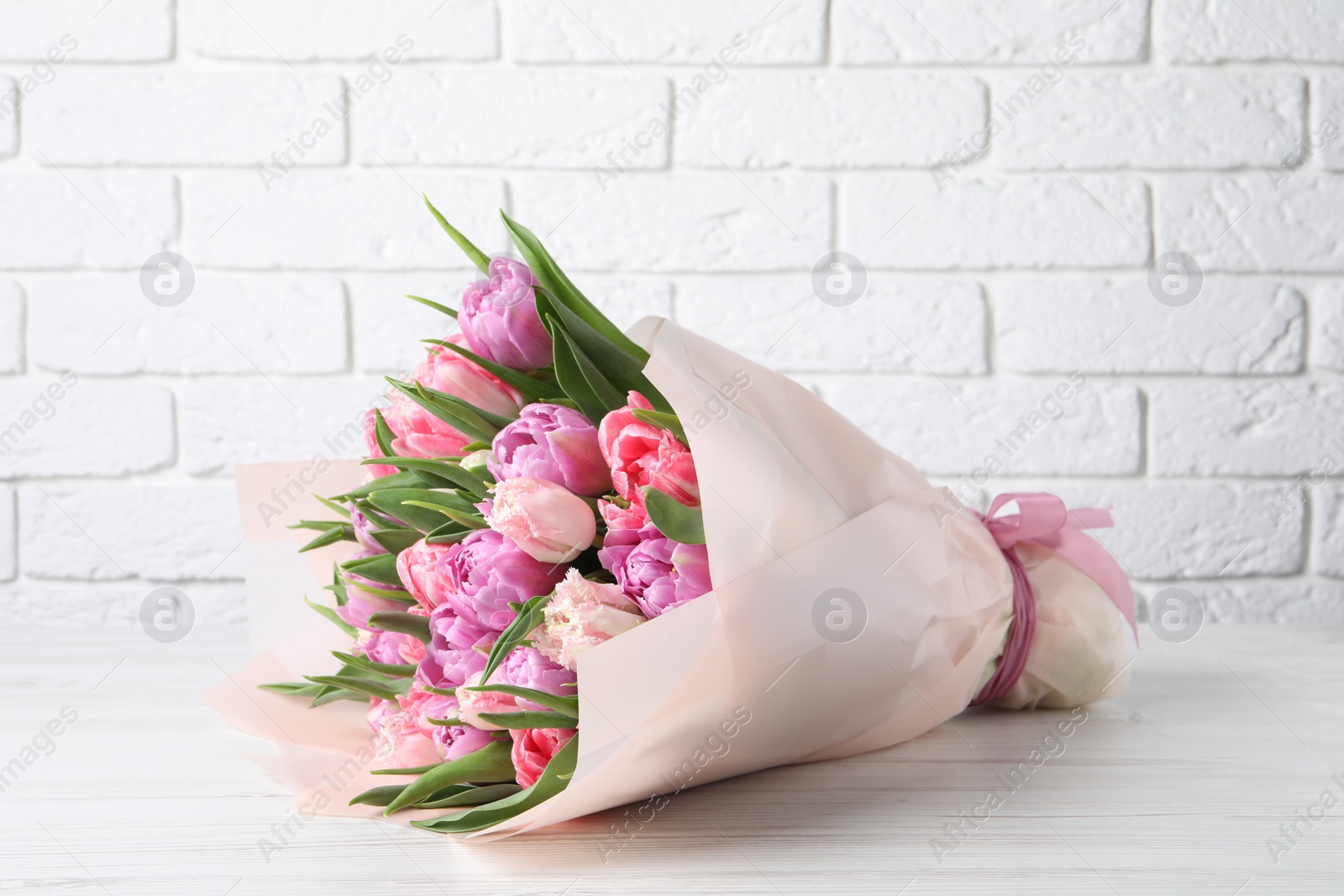 Photo of Bouquet of beautiful tulips on white wooden table
