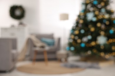 Photo of Christmas tree in room decorated for holiday, blurred view. Festive interior