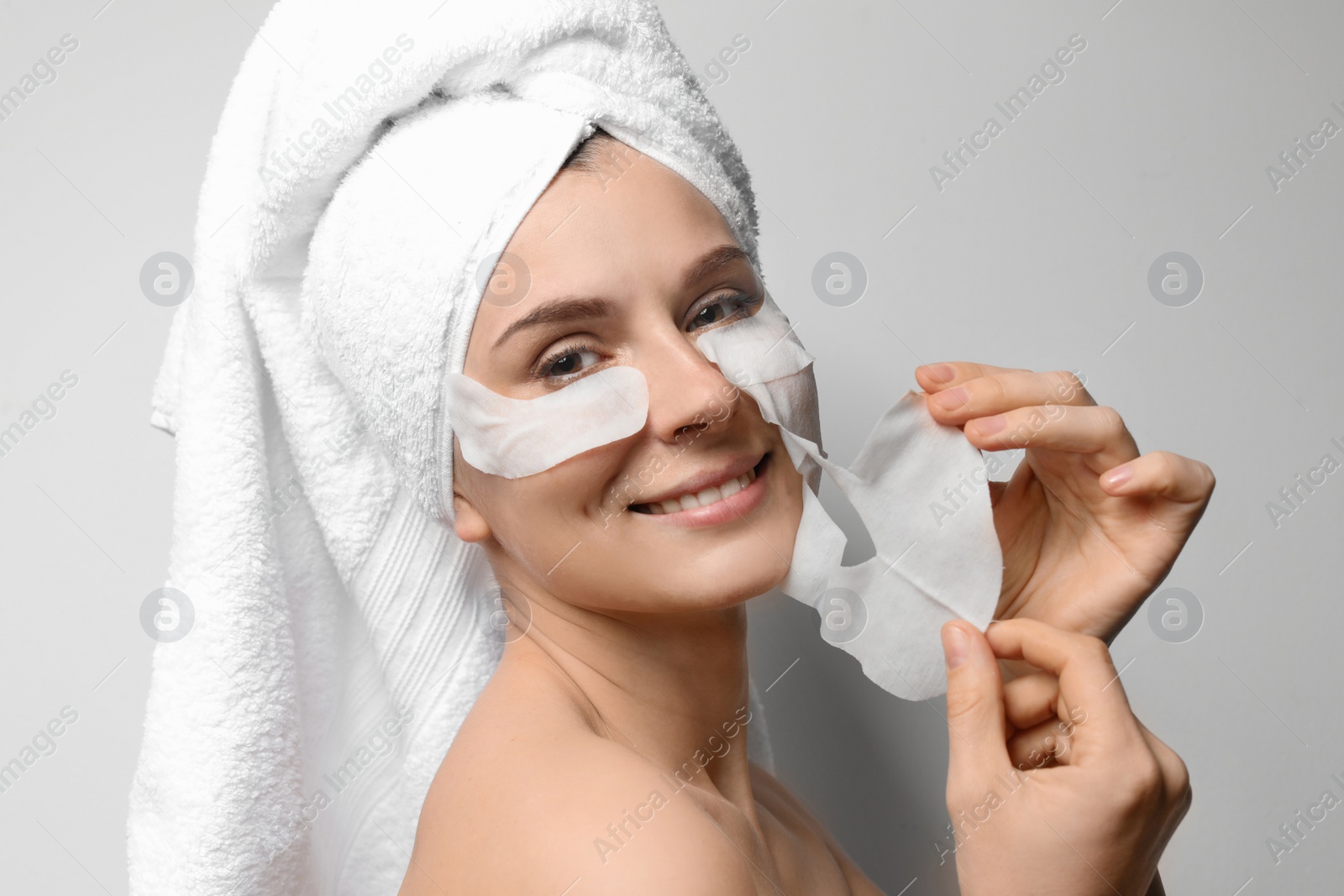 Photo of Beautiful woman with cotton face and eye masks against light background