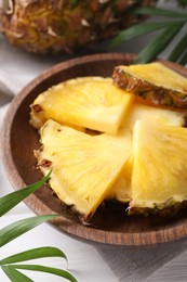 Pieces of tasty ripe pineapple in bowl on table, closeup