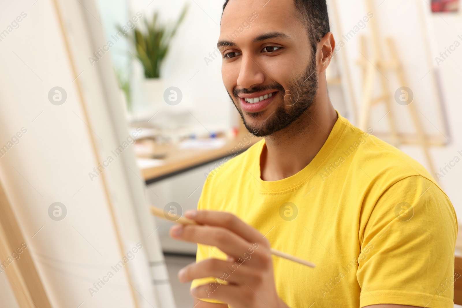 Photo of Young man painting with brush in studio. Creative hobby