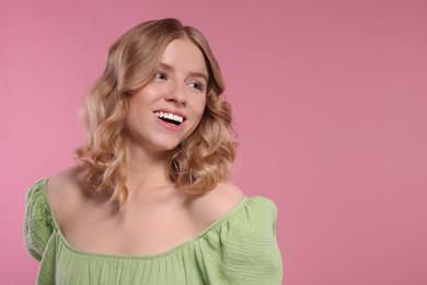 Portrait of beautiful woman with blonde hair on pink background