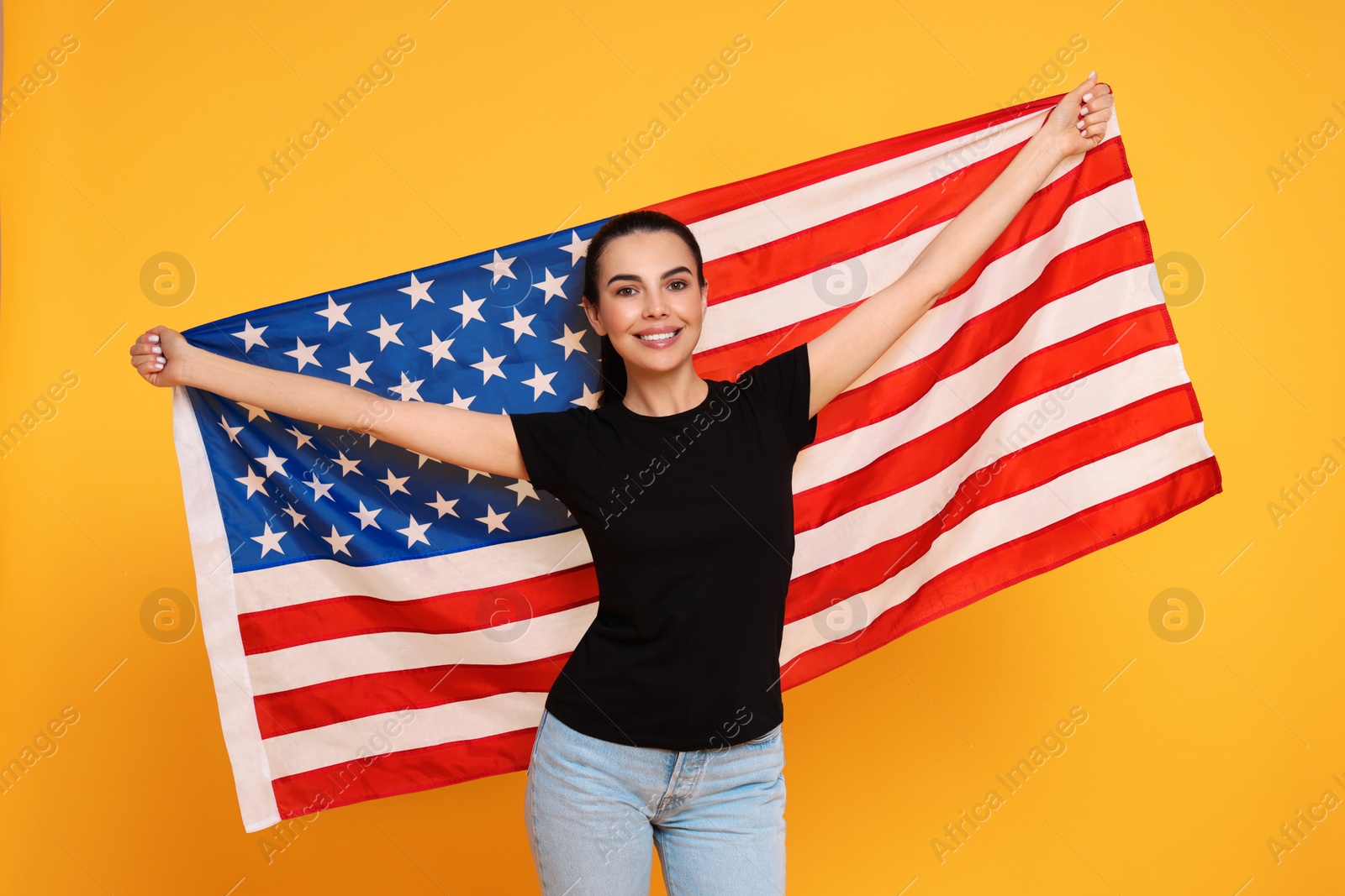 Photo of 4th of July - Independence Day of USA. Happy woman with American flag on yellow background