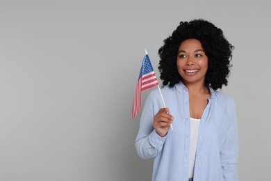 Photo of 4th of July - Independence Day of USA. Happy woman with American flag on light grey background, space for text