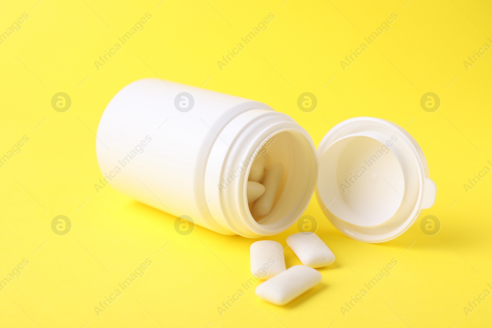 Photo of Jar with chewing gums on yellow background, closeup