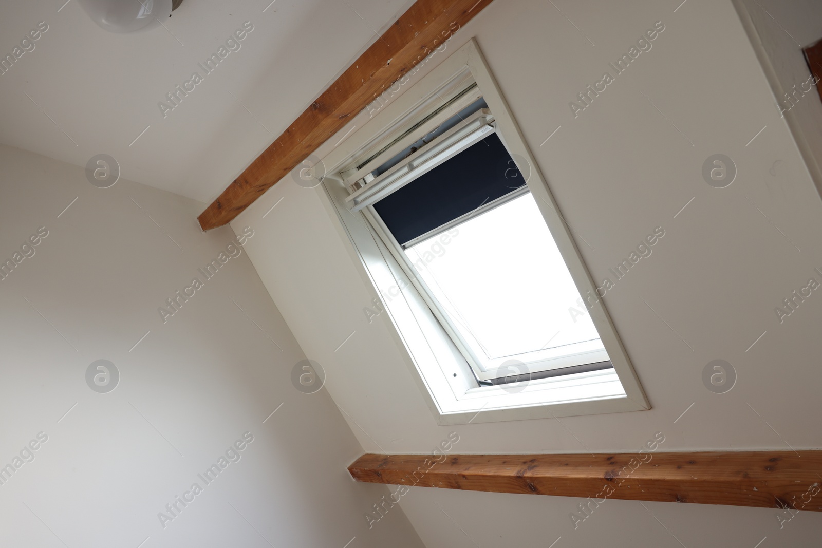 Photo of Roof window on slanted ceiling indoors, low angle view