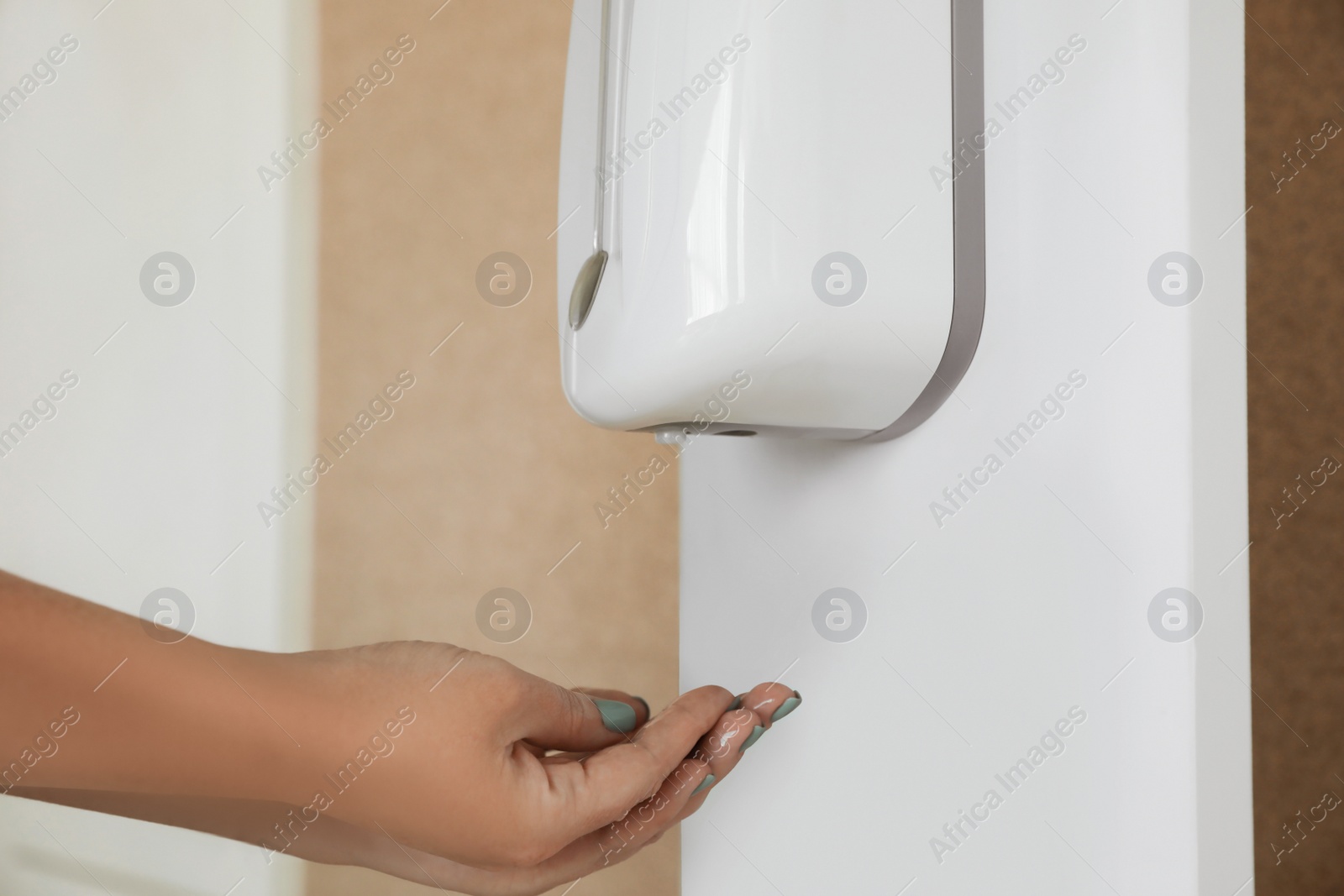Photo of Woman using automatic hand sanitizer dispenser indoors, closeup