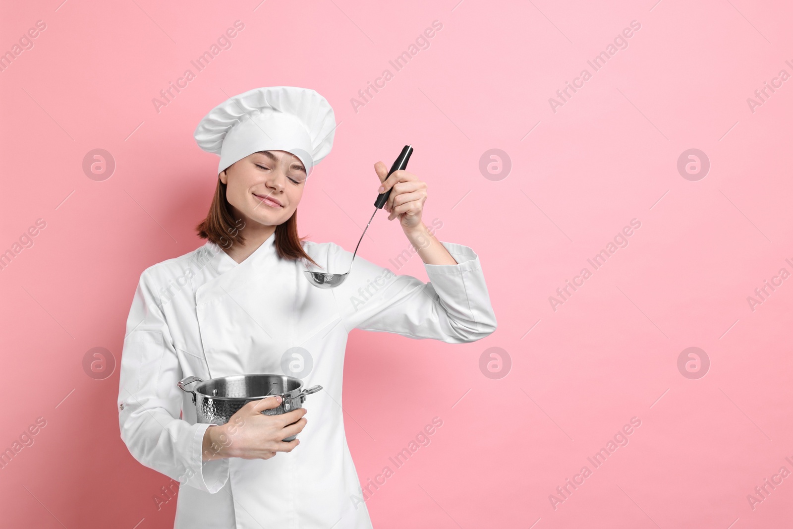 Photo of Professional chef cooking pot and ladle on pink background. Space for text