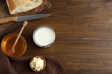 Photo of Flat lay composition of honey, milk and butter on wooden table. Space for text