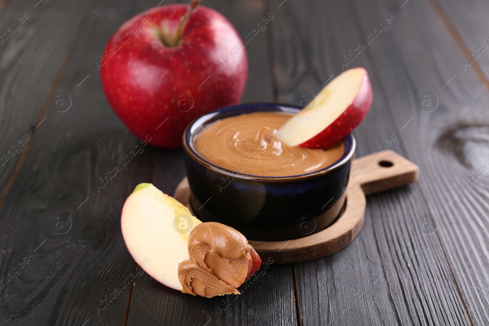 Photo of Slices of fresh apple with peanut butter on wooden table, closeup