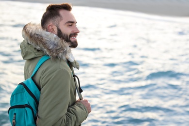 Photo of Stylish young man with backpack near sea
