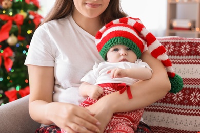 Photo of Young woman with baby in Christmas hat at home