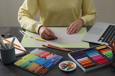 Photo of Artist drawing with soft pastels at table indoors, closeup
