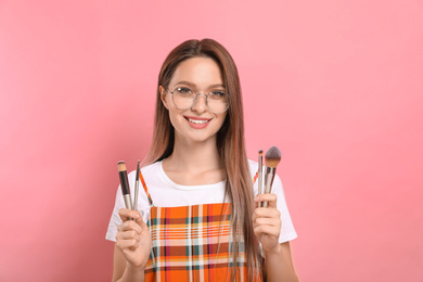 Beauty blogger with set of make up brushes on pink background