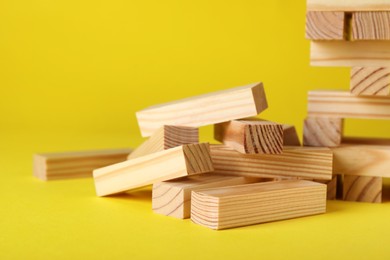 Photo of Wooden Jenga blocks on yellow background, closeup