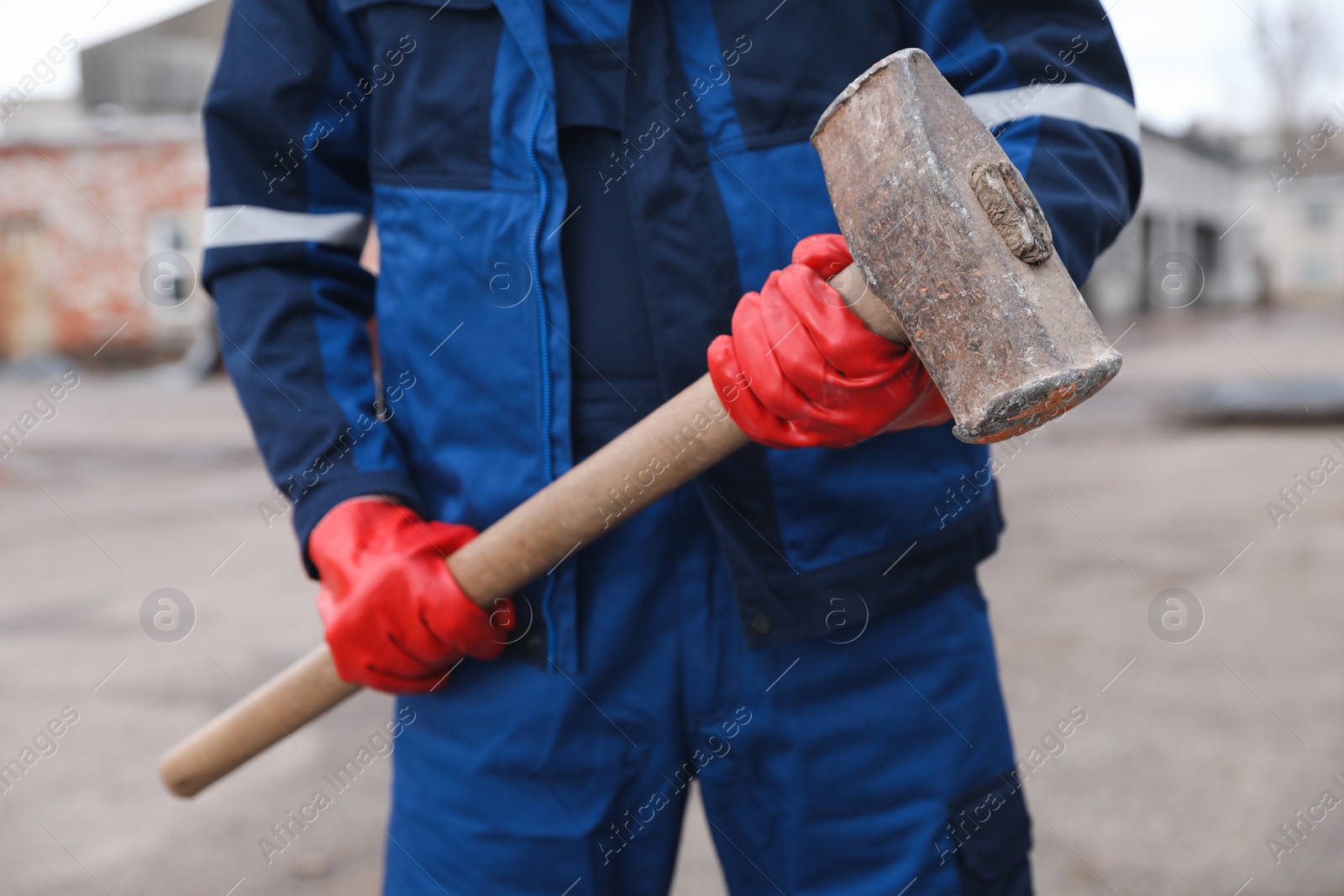 Photo of Man in uniform with sledgehammer outdoors, closeup