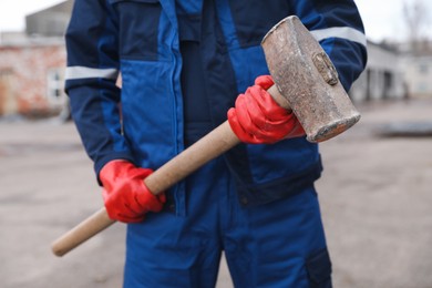 Man in uniform with sledgehammer outdoors, closeup