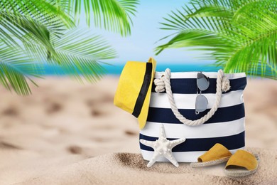 Stylish bag with different accessories on tropical sandy beach, space for text 