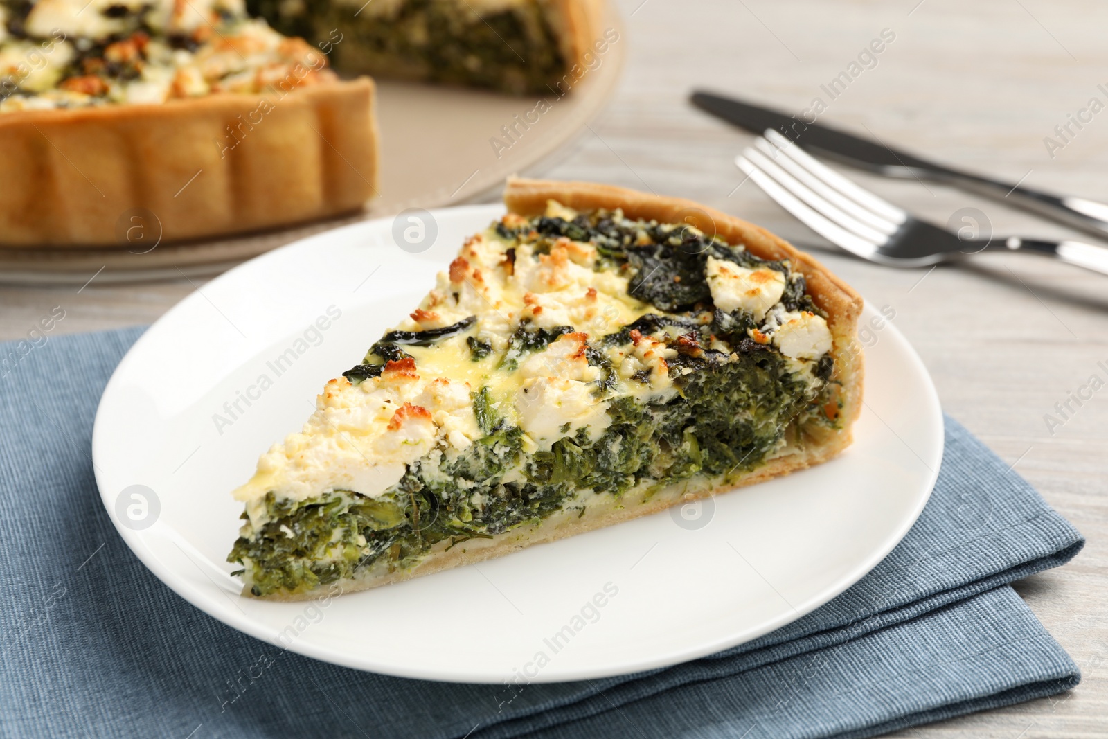 Photo of Piece of delicious homemade spinach quiche on table