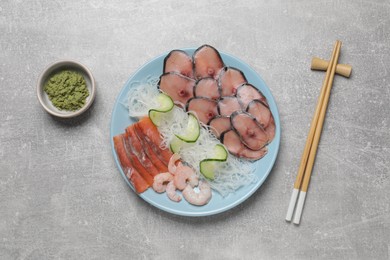 Set with raw salmon, mackerel slices, shrimps served with cucumber, funchosa and vasabi on light grey table, flat lay