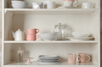 Stylish storage stand with different ceramic dishware at home