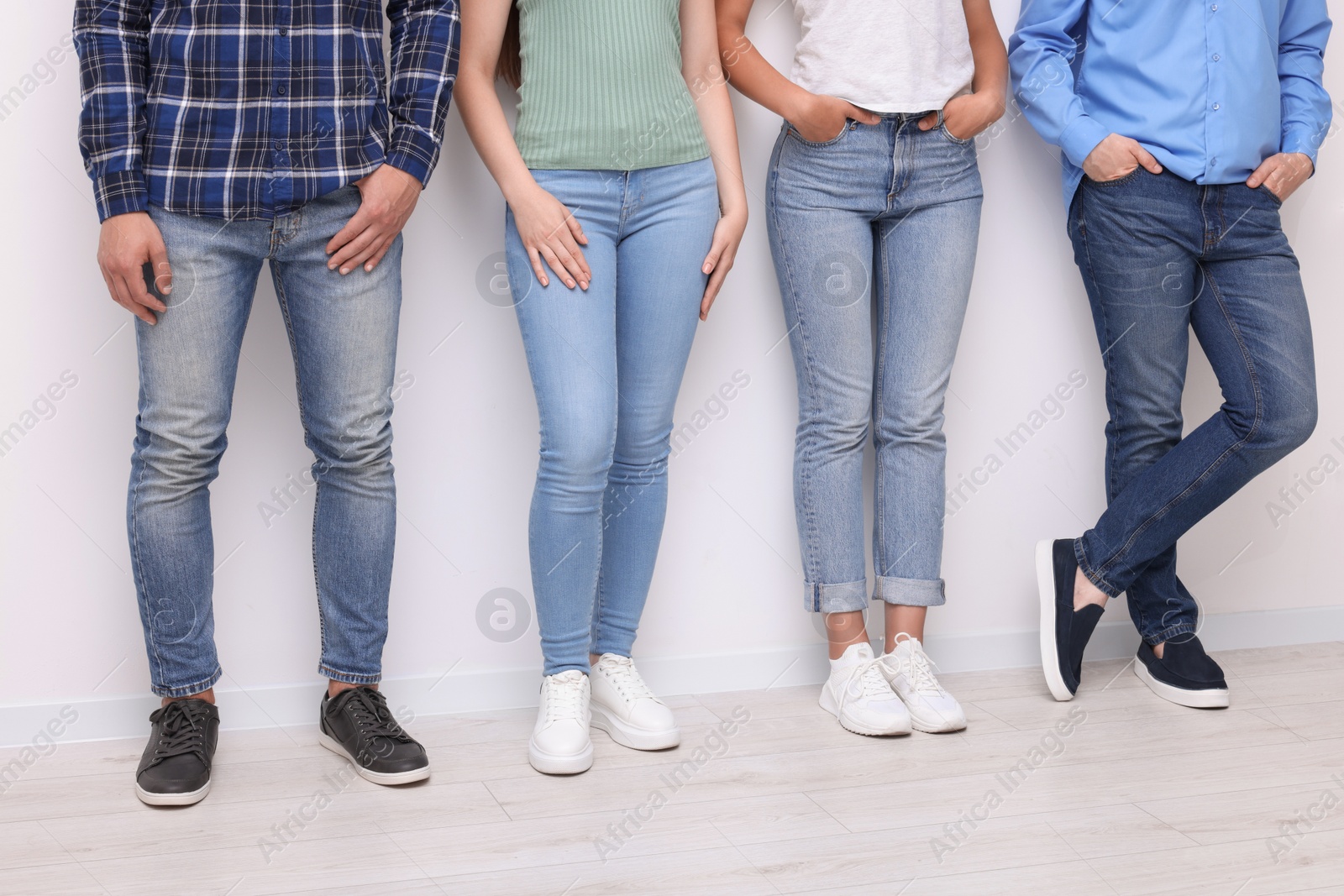 Photo of Group of people in stylish jeans near white wall indoors, closeup