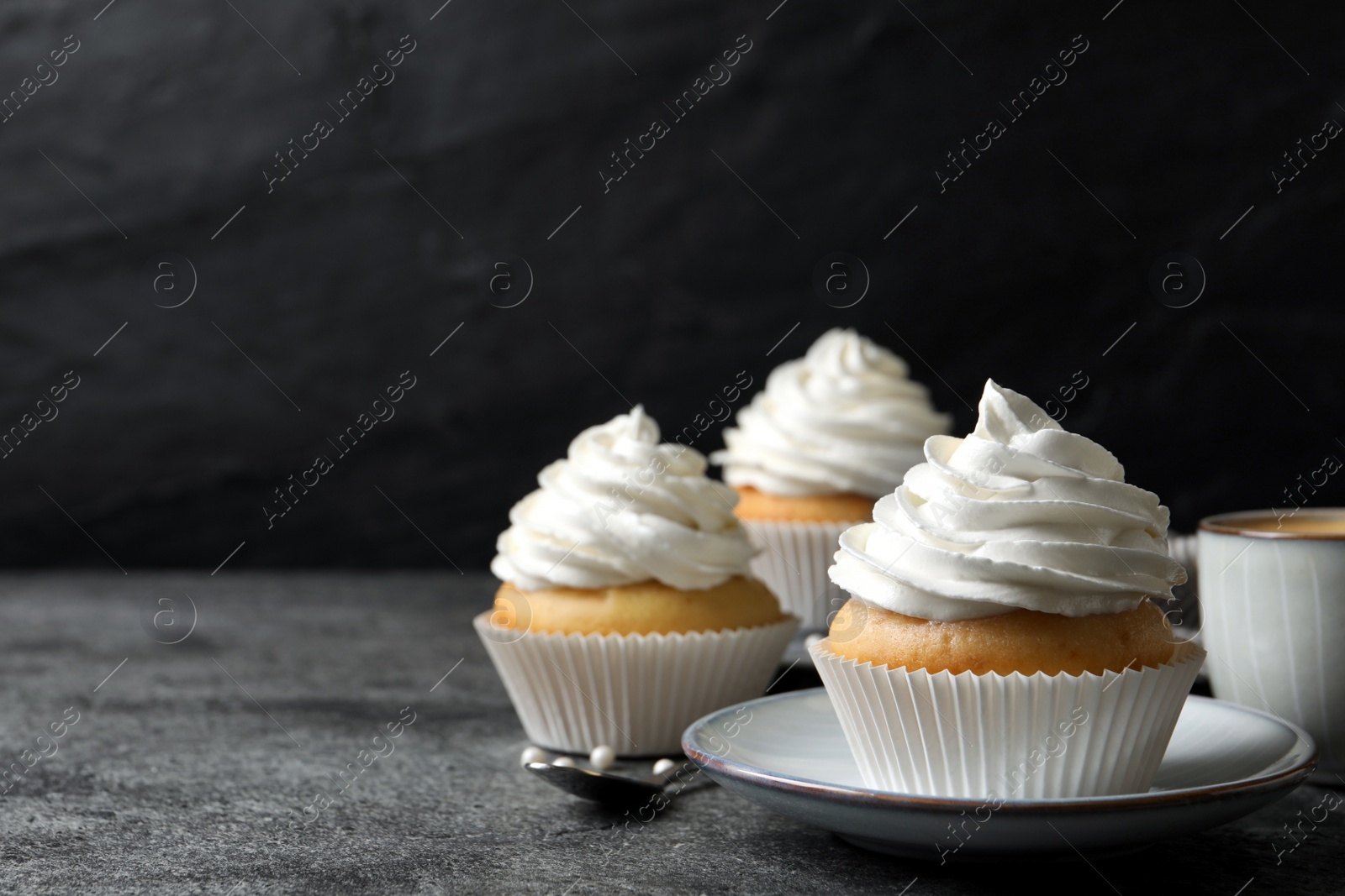 Photo of Delicious cupcakes with cream on grey table. Space for text