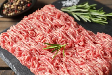 Photo of Raw ground meat and rosemary on table, closeup